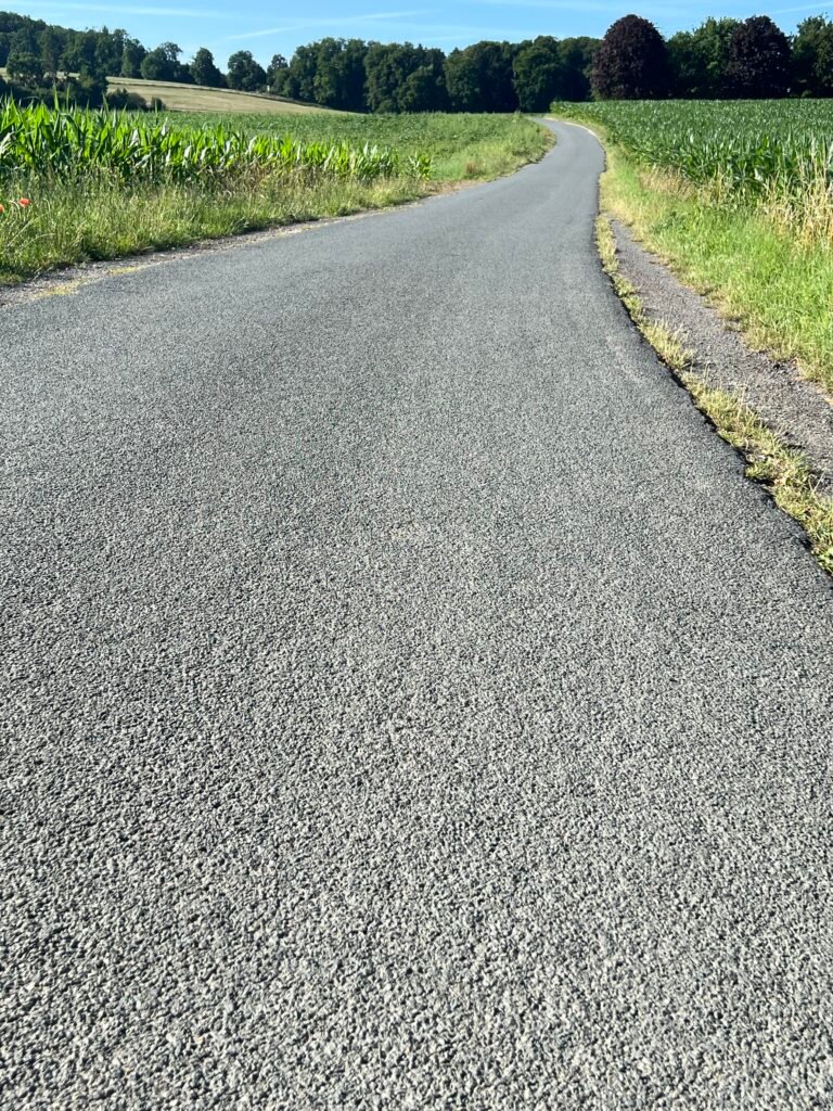Asphaltierte Straße mit Feldern links und rechts